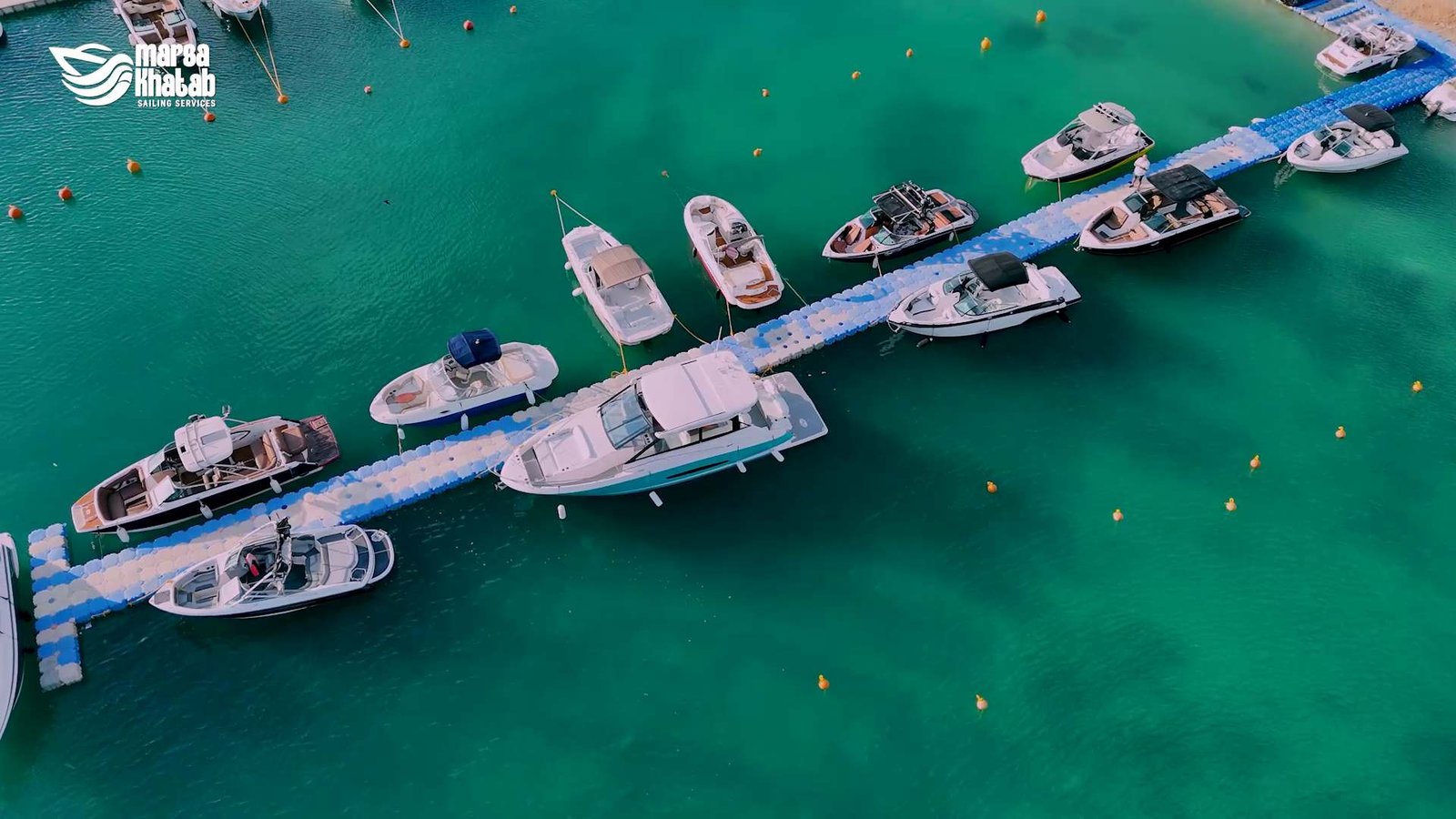 Aerial view of yachts moored at floating pontoons in Marsa Khatab Marina's turquoise waters